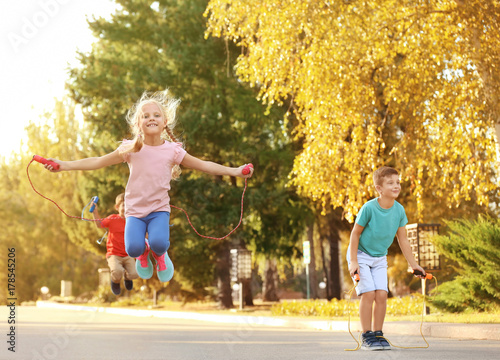 Adorable children skipping rope outdoors