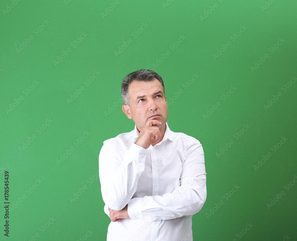 Mature man in white shirt on color background