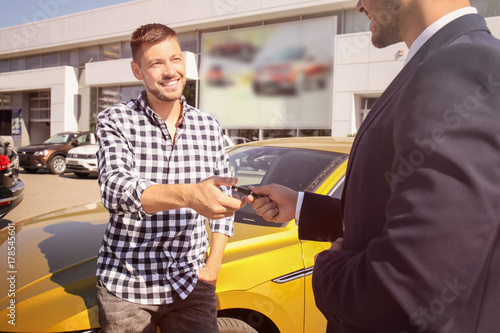Salesman giving key to cust...