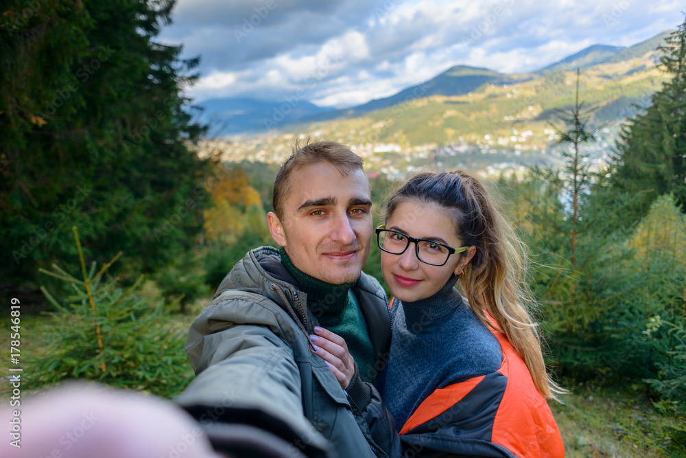 Happy lucky couple makes a self portrait against the background of mountains and towns. A couple of tourists doing sephi in the mountains.
