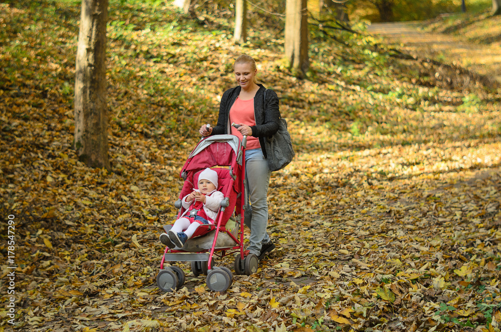 Young mother walking with her baby and carries it in a stroller