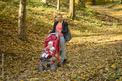 Young mother walking with her baby and carries it in a stroller