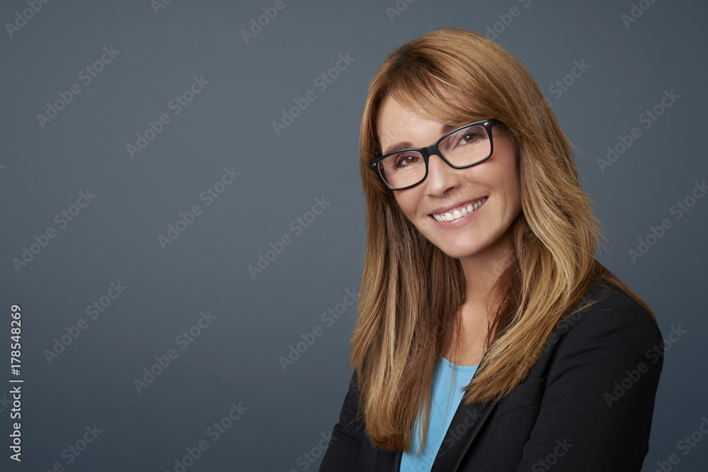Attractive middle aged businesswoman against grey background. Attractive middle aged businesswoman against grey background.