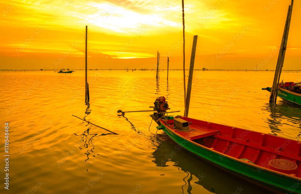 Fisherman's boat floating in the sea near bamboo pole at sunset in Thailand.