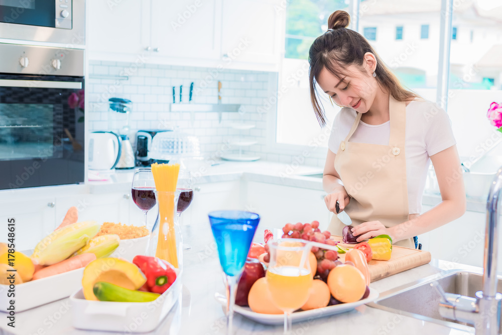 Woman cooking and slicing vegetable in kitchen room with full of food and fruit on table. Holiday and Happiness concept. Woman cooking and slicing vegetable in kitchen room with full of food and fruit on table. Holiday and Happiness concept.