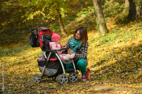 Obraz na płótnie Young mother walking with her baby and carries it in a stroller w salonie