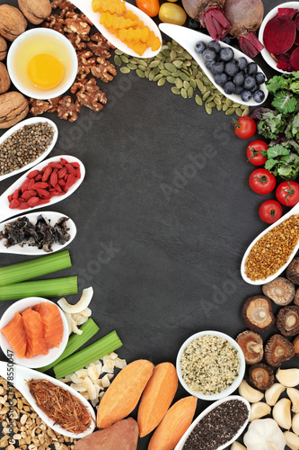 Brain boosting health food background border with fish, vegetables, seeds, nuts, fruit, herbs and pollen grain on slate. Foods high in omega 3, vitamins, minerals, antioxidants and anthocyanins. 