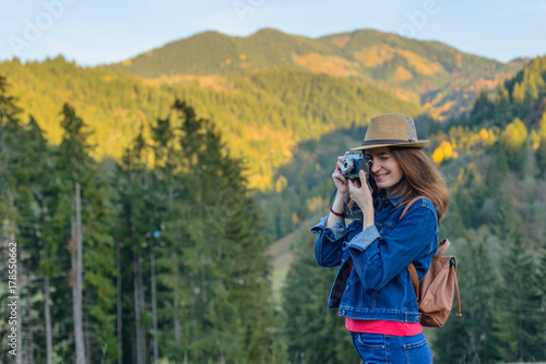 Happy smiling girl photographer photographing mountain landscapes. Woman a traveler with a cameraon a hiking in the mountains
 photo