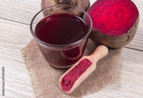 Healthy beetroot juice and fresh vegetables on wooden background.