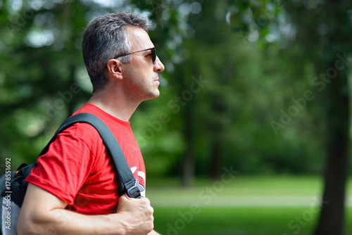 Portrait of handsome middle-aged man in profile in summer park.