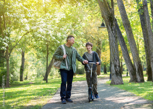 Portrait of father with his son walking together in autumn park. Family leisure. Parenting. Parenthood. photo