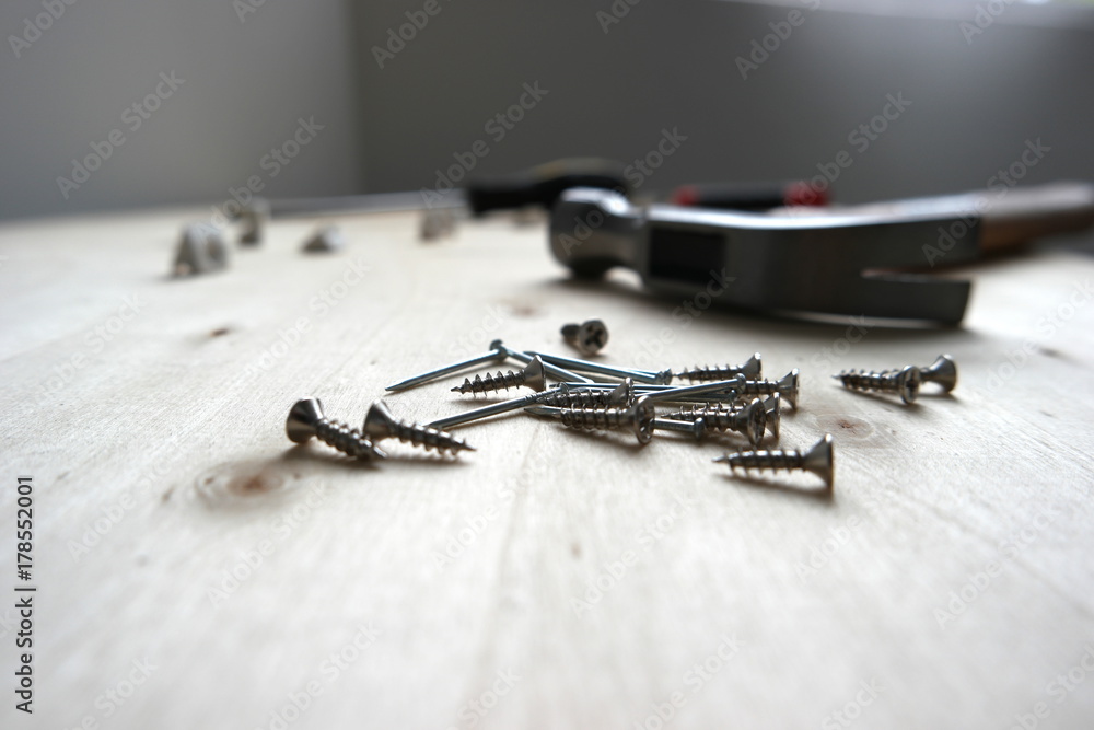 Nails, screws, and a hammer on home improvement construction site Nails, screws, and a hammer on home improvement construction site