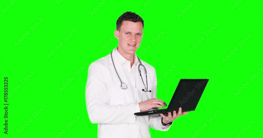 Male Caucasian doctor using a laptop computer while standing in the studio with green screen background, shot in 4k resolution Male Caucasian doctor using a laptop computer while standing in the studio with green screen background, shot in 4k resolution
