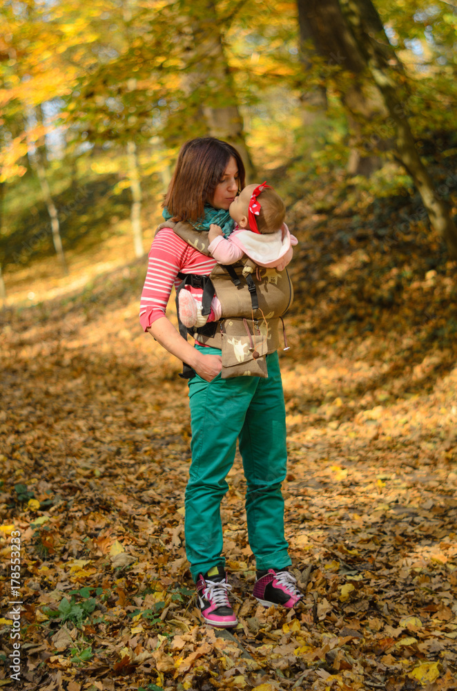 Mother carrying her baby daughter in ergonomic backpack for children