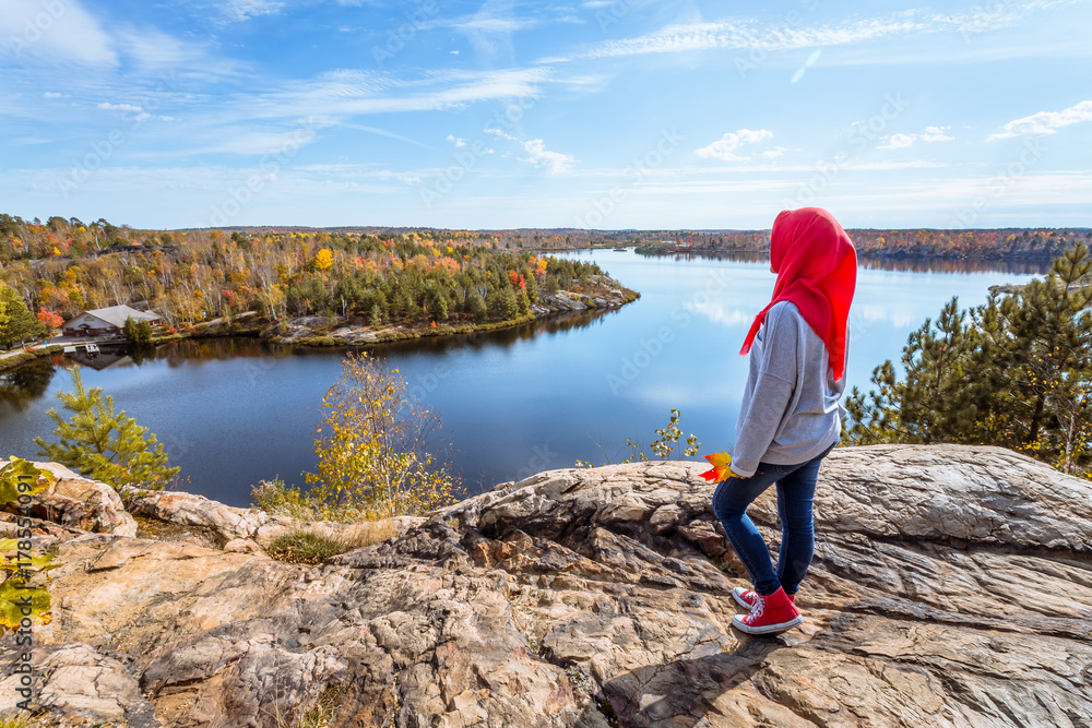 A muslim teenager enjoying view of a lake from top of the hill during fall season