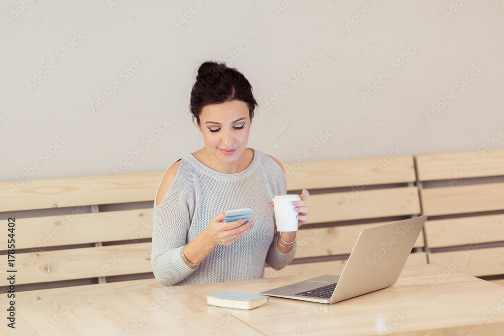 Concentrated at work woman. Confident young woman in casual wear working on laptop and mobile phone while sitting in creative office or cafe Concentrated at work woman. Confident young woman in casual wear working on laptop and mobile phone while sitting in creative office or cafe