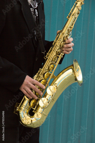 close up of street saxophone Player hands playing alto sax musical instrument over blue background   closeup with copy space  can be used for music background