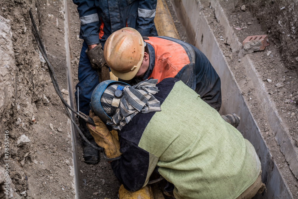 A man welder looks at a pipe section for welding A man welder looks at a pipe section for welding