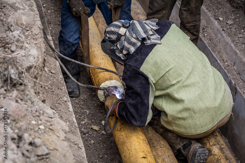 A man welder cooks a pipe at the point of rupture