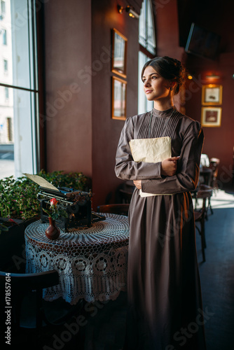 Serious dark hair lady stands near table