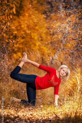 beautiful woman doing yoga outdoors On yellow leaves photo