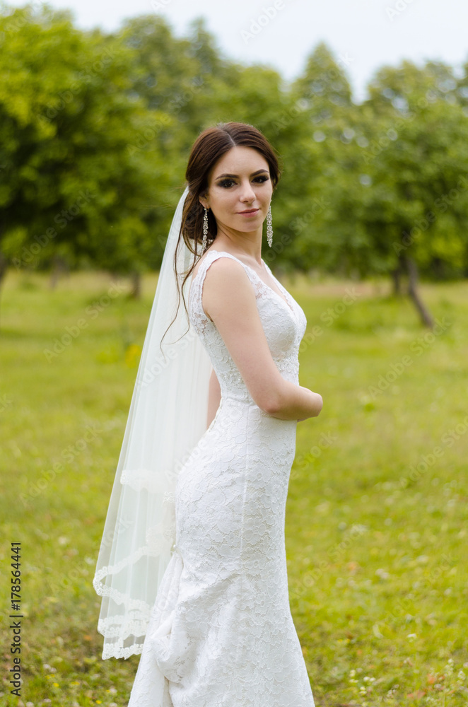 A beautiful married girl in wedding dress, posing for a photo shooting in an belarusian village. Green background A beautiful married girl in wedding dress, posing for a photo shooting in an belarusian village. Green background