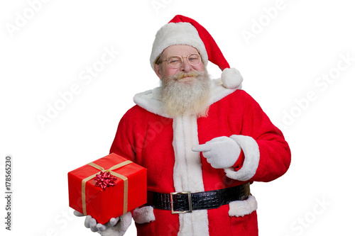 Portrait of Santa Claus with present. Man in costume of Santa Claus standing on white background and holding Christmas present. Santa pointig on red gift box with bow. photo