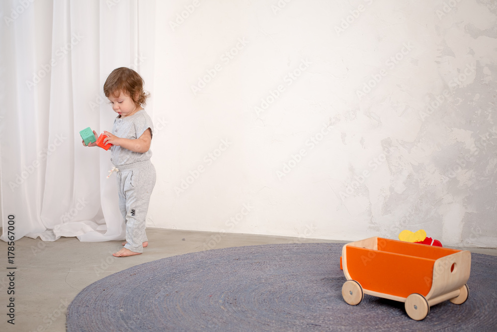 Naklejka premium Little happy girl playing with toy on floor. Kindergarten.