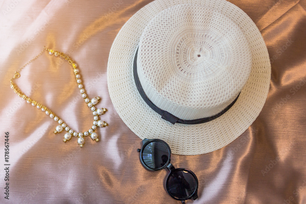 woman hat and sun glasses with accessory on bed woman hat and sun glasses with accessory on bed