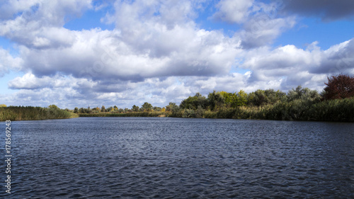 A river with autumn trees and beautiful clouds. Travels. Fishing