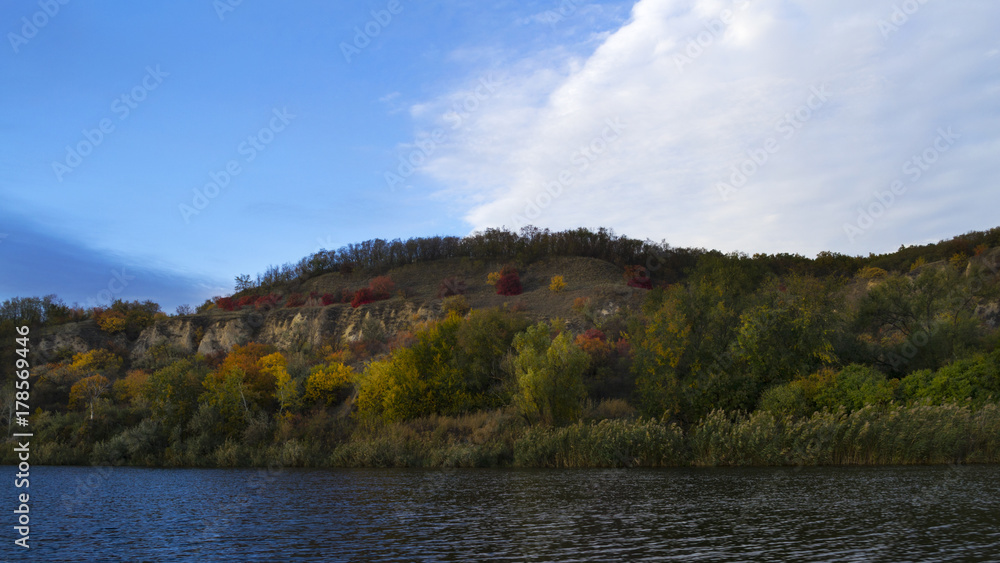 A river with autumn trees and beautiful clouds. Travels. Fishing