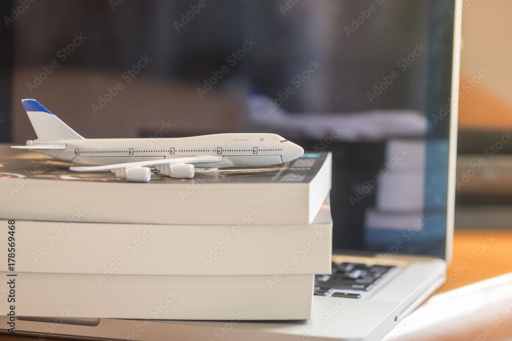 custom made wallpaper toronto digitalTravel and information Concept. Mini airplane toy model on books and laptop computer on wooden table
