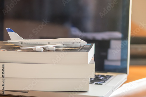 Wallpaper Mural Travel and information Concept. Mini airplane toy model on books and laptop computer on wooden table Torontodigital.ca