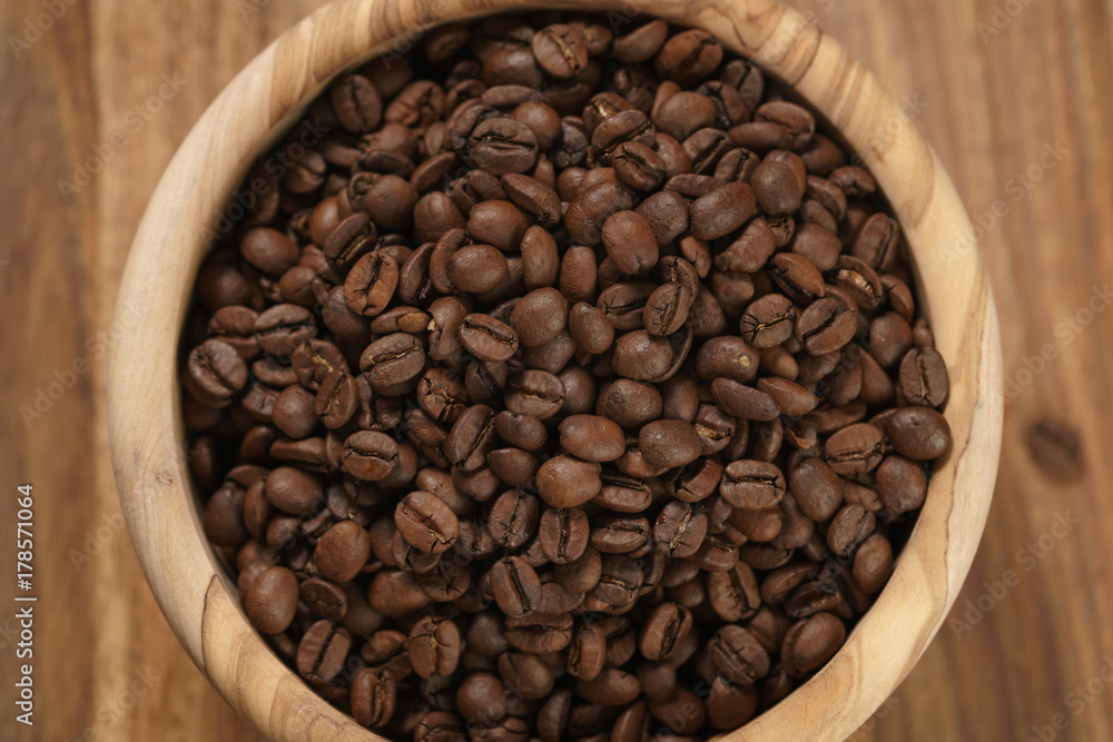 Fototapeta premium roasted coffee beans in wood bowl on table