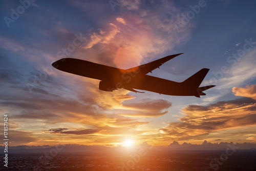 The silhouette of a passenger plane flying in sunset.