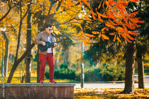 Portrait handsome man playing bass ukulele in the park Music concept