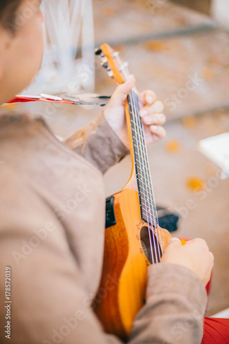 close up finger of ukulele guitarist while playing guitar in the outdoor garden