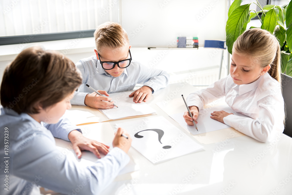 Intelligent cute children are writing on sheet of paper Intelligent cute children are writing on sheet of paper