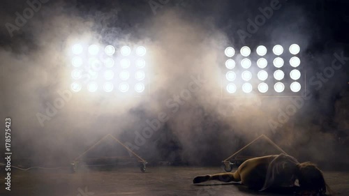 a young woman of pleasant appearance dances in the training hall in the lighting of searchlights in the background. a professional dance girl performs the set number in the style of lacquering and