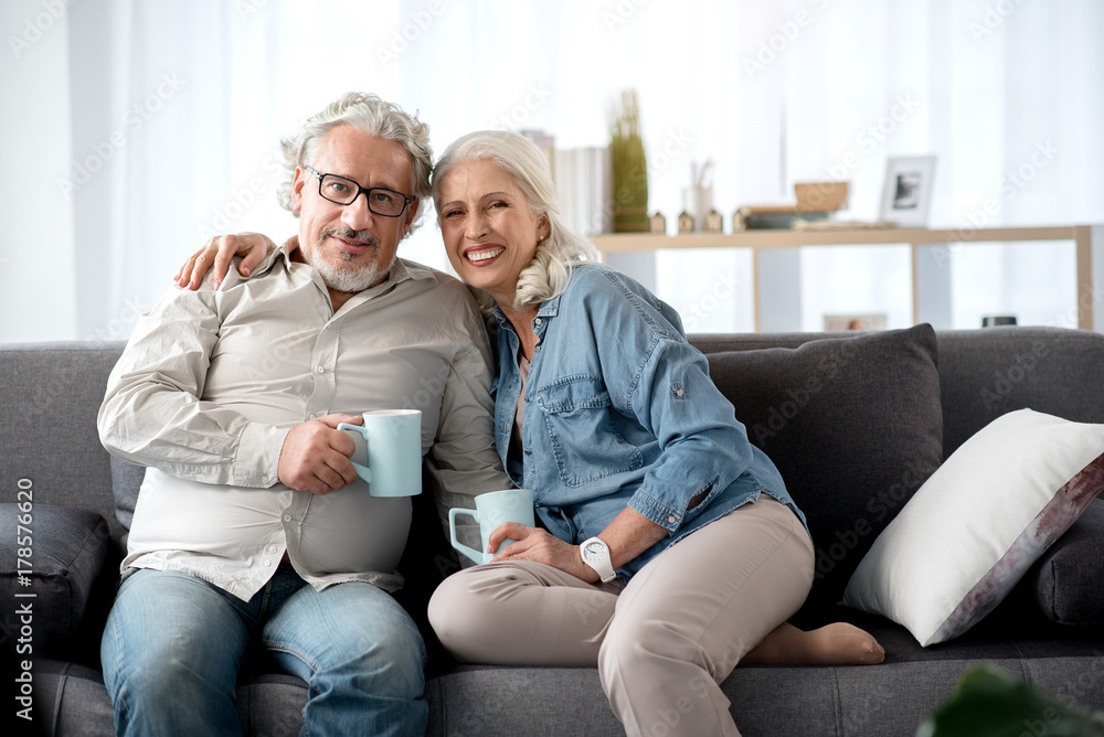 Joyful mature man and woman resting on couch at home