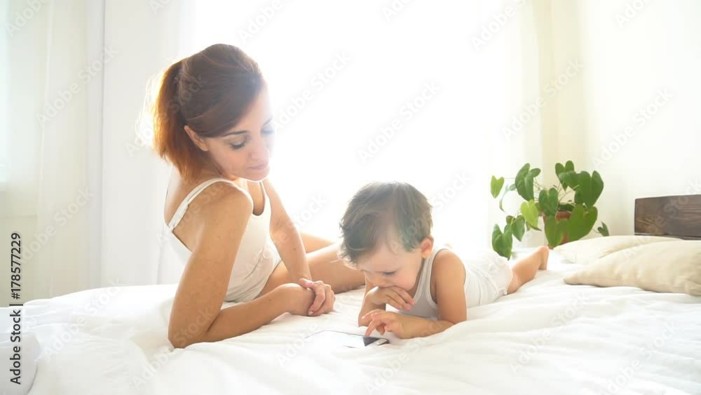 mom and baby look at smartphone in the bedroom mom and baby look at smartphone in the bedroom