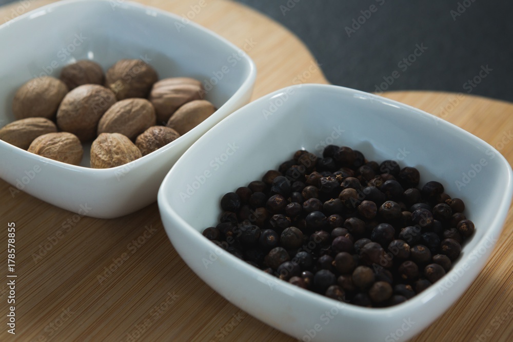 Nutmegs and black pepper seeds in chopping board Nutmegs and black pepper seeds in chopping board
