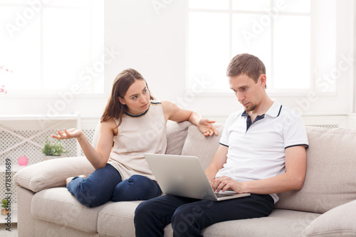 Angry woman sitting while husband using laptop