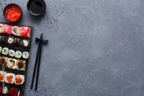 Top view set of sushi maki and rolls on rustic grey and sesame background