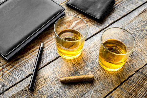 Drink whiskey in the evening. Glasses, wallet, cigar on rustic wooden background