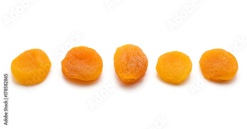 Five whole dried apricots in row isolated on white background