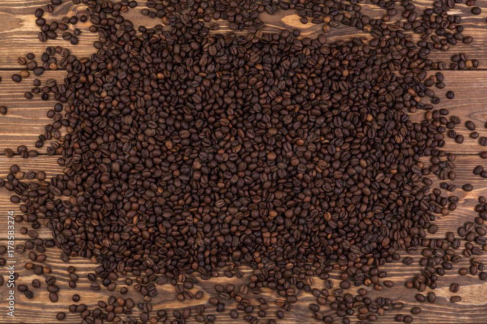 Fototapeta premium Coffee beans on brown wooden background, coffee texture, top view
