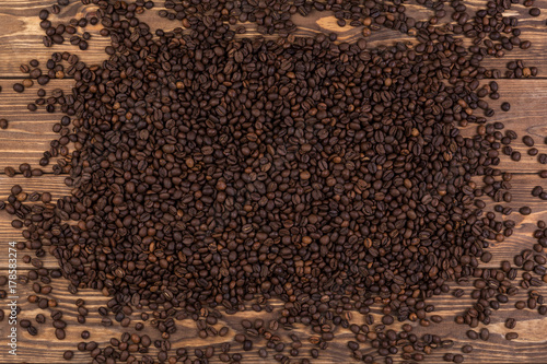 Coffee beans on brown wooden background, coffee texture, top view