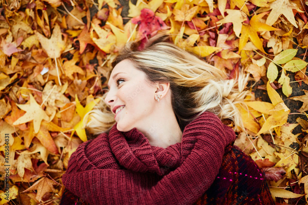 young blond woman laying on autumn leaves young blond woman laying on autumn leaves