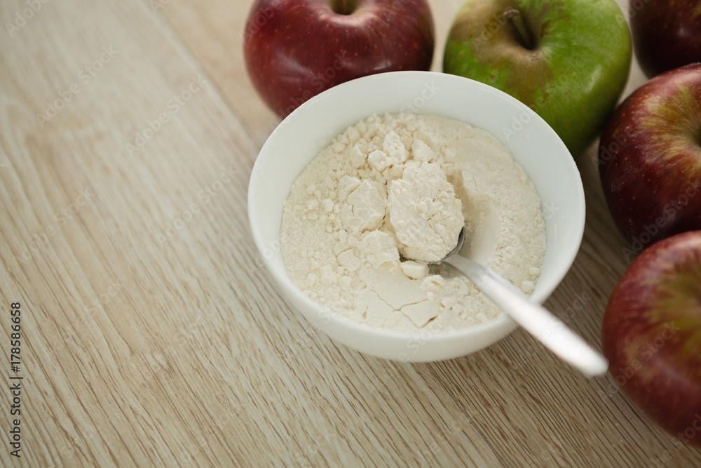 Close up of flour in bowl by apples